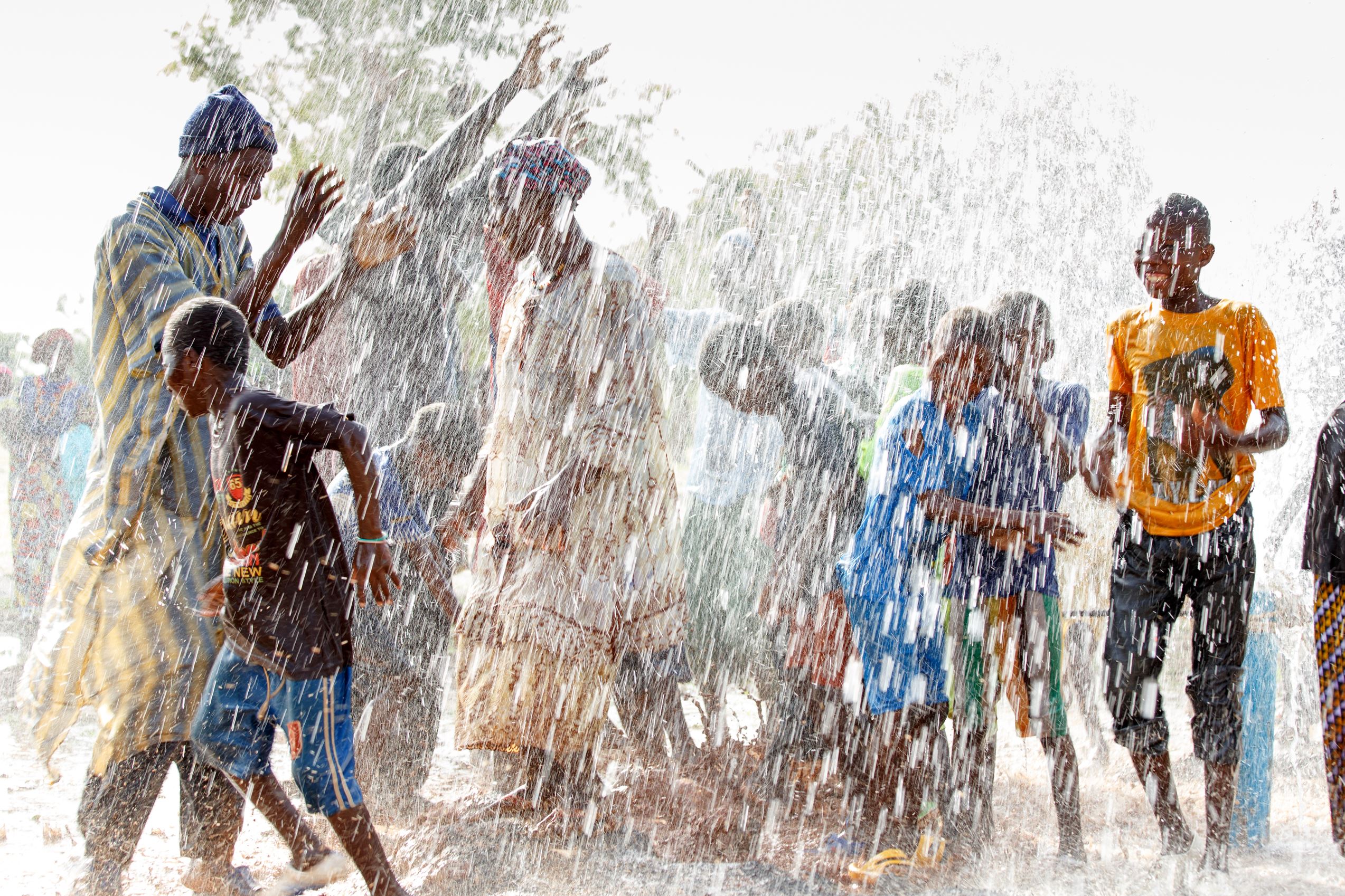 A community in Mali dancing in the flowing water to celebrate World Vision’s 150,000th borehole in the country