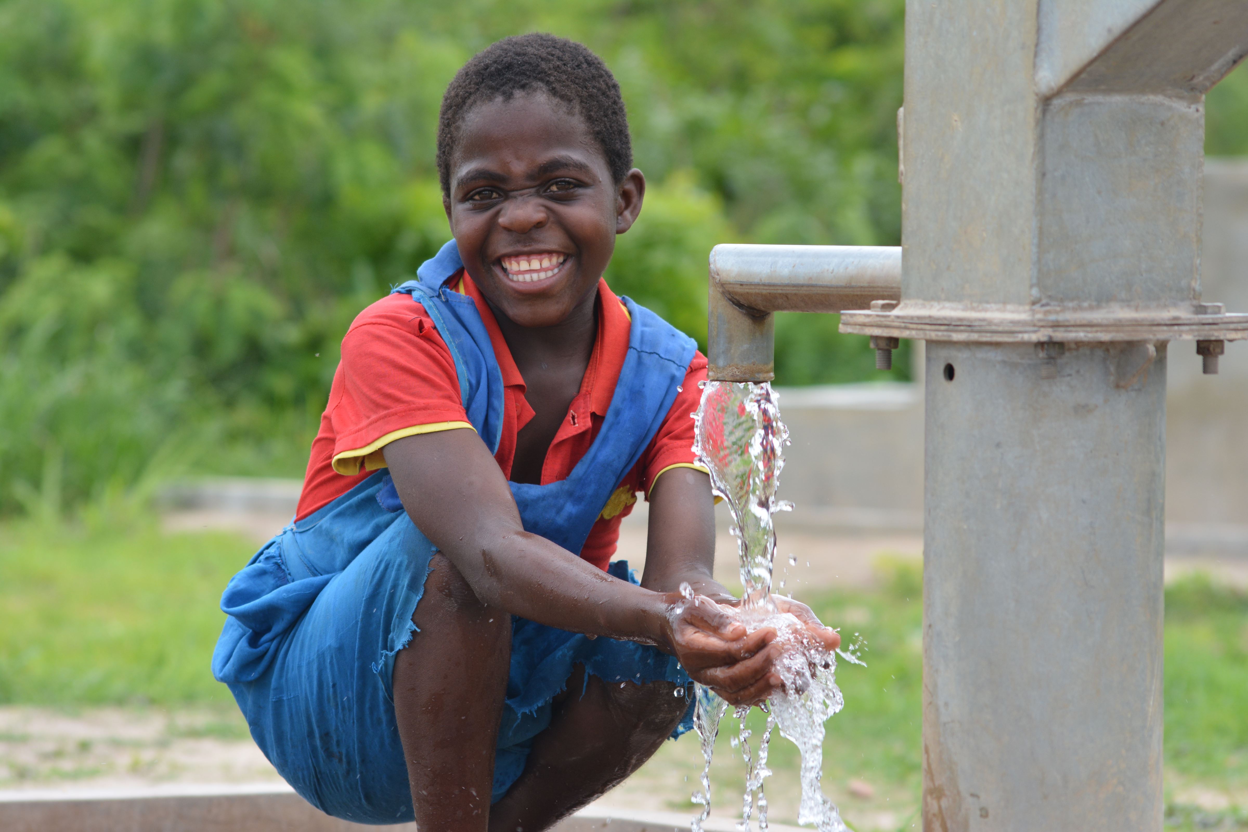 A girl from Malawi is happy to access clean and safe drinking water from a borewell