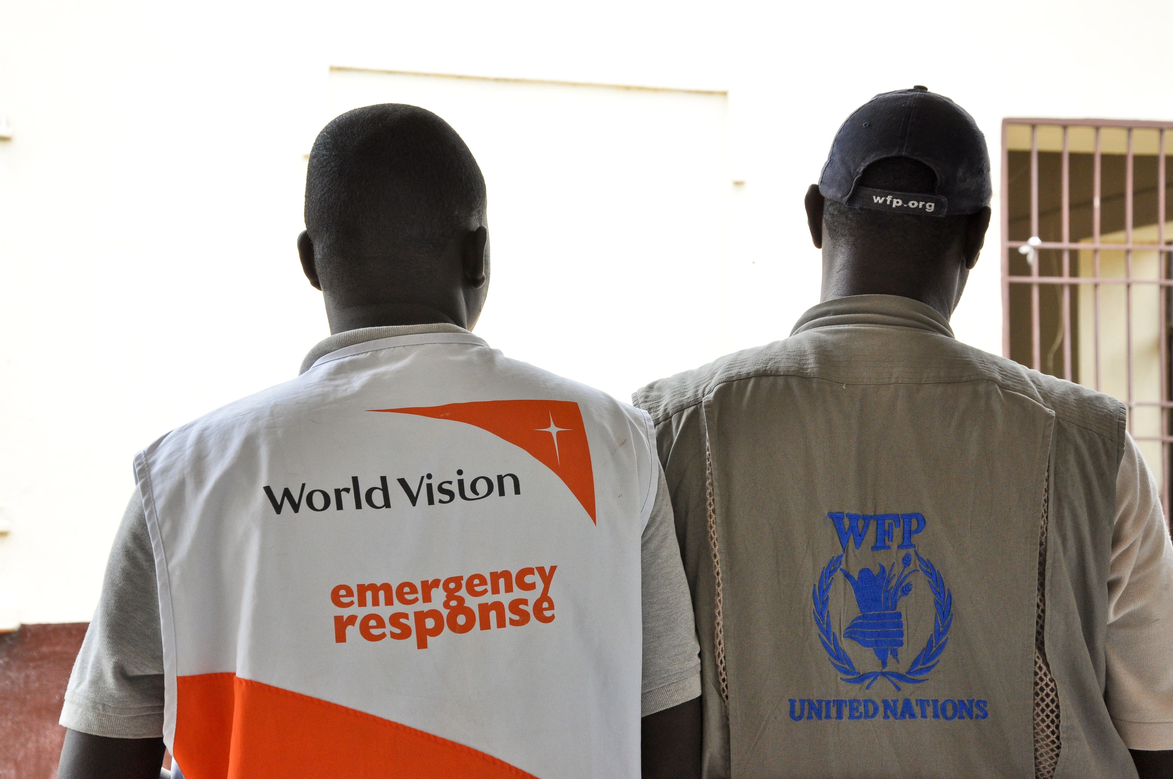 World Vision staff member stands shoulder to shoulder with a World Food Programme Staff Member