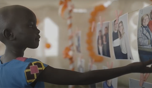 Girl reaches towards a photograph of people she is considering choosing to be her sponsor