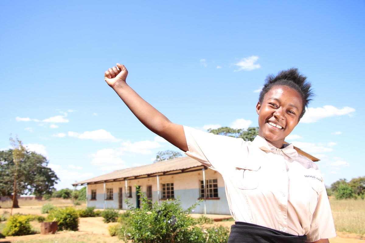 School girl smiles and raises fist at school in Zambia